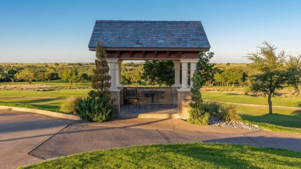 Stone-clad gazebo with column supports and a shingle roof