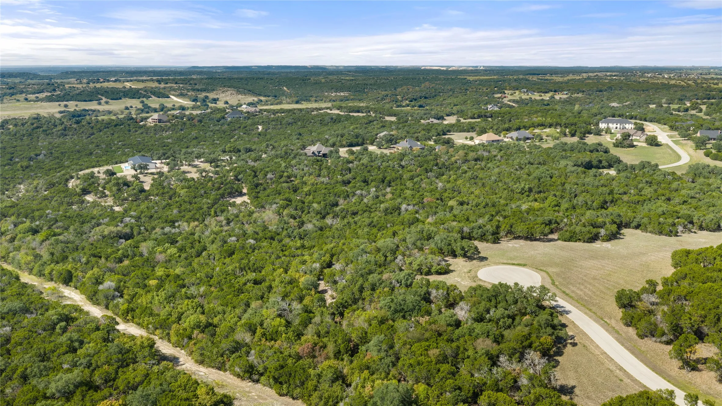 Expansive wooded terrain with scattered residential properties and paved road access