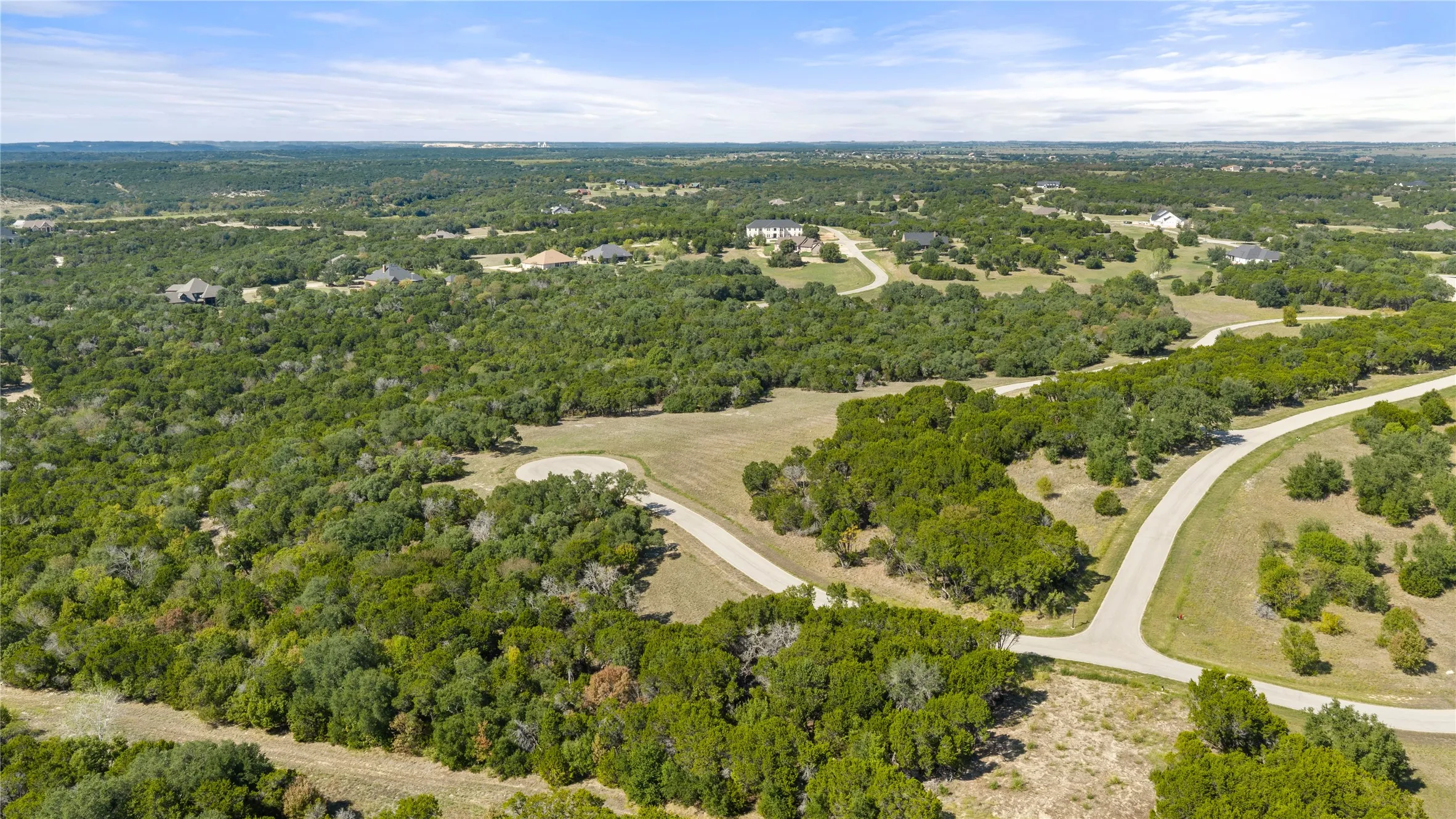 Expansive landscape with abundant mature trees and paved roadways