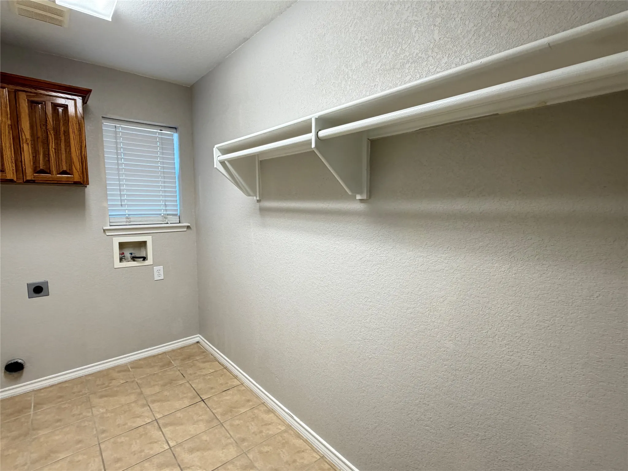 Built-in storage shelving, wood-finish cabinetry, tiled flooring, and a window with blinds