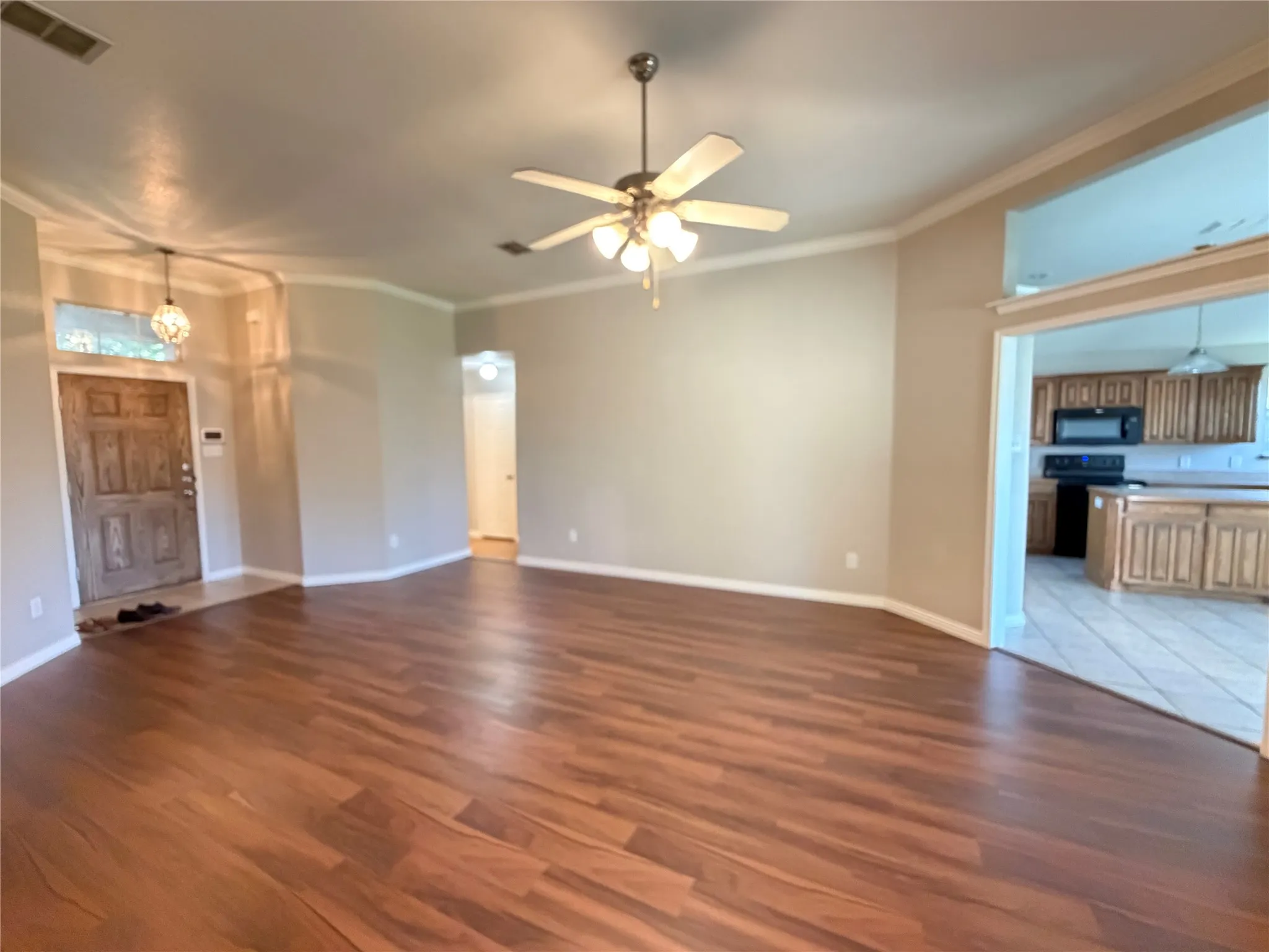 Wood-finish flooring, crown molding, ceiling fan, recessed lighting, and a paneled entry door