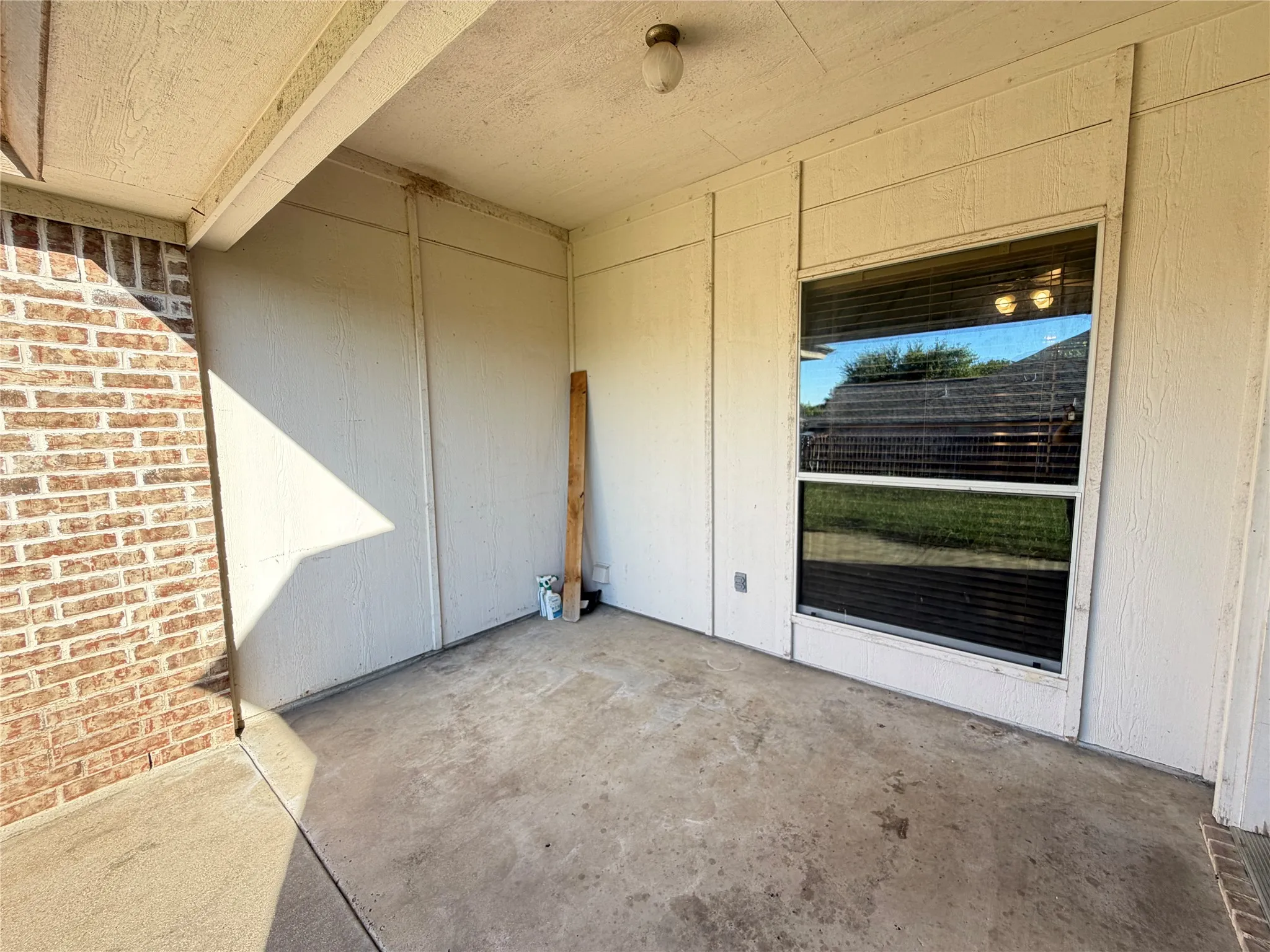 Covered patio featuring a concrete slab and a brick exterior wall
