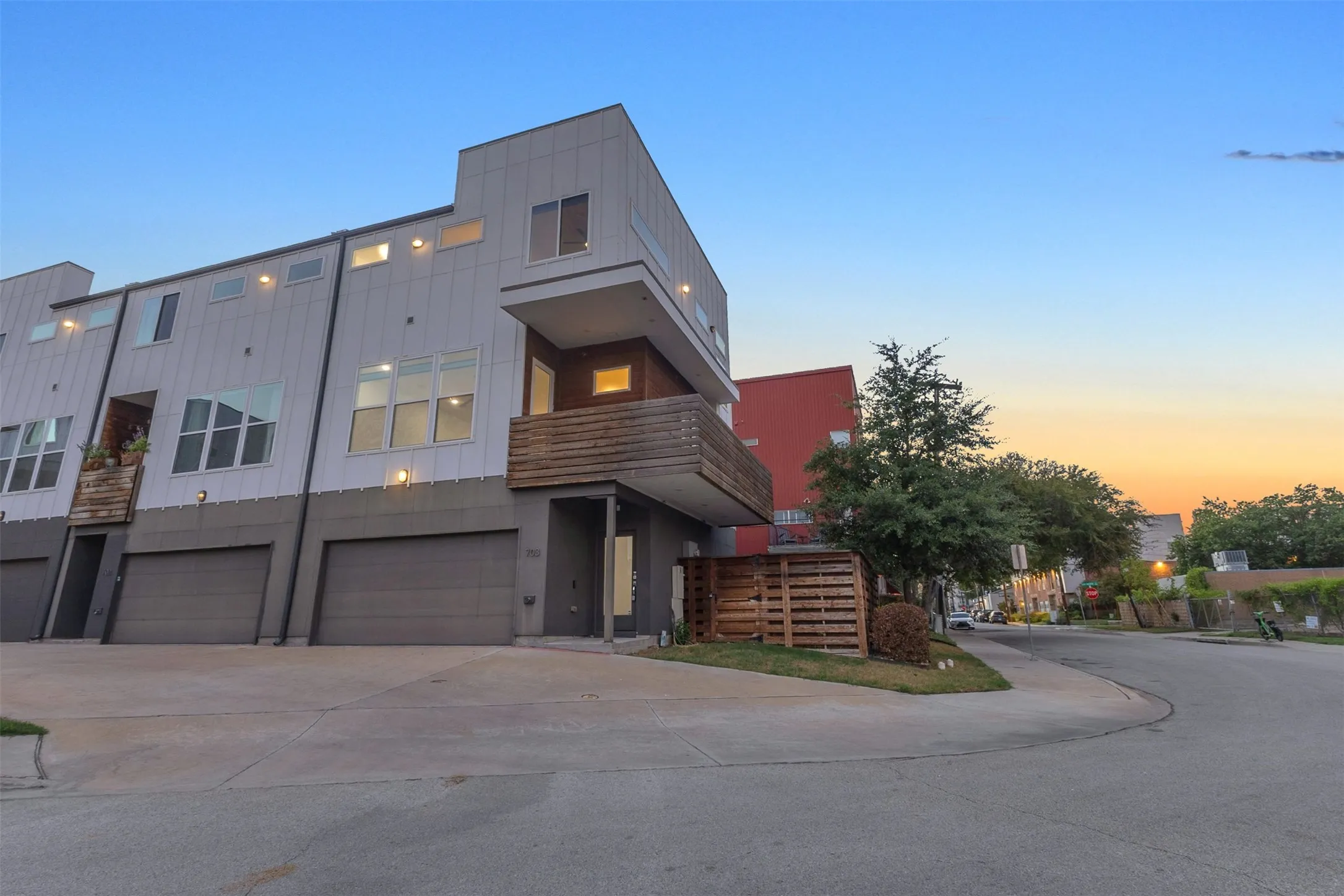 Street view of the corner end unit with board and batten siding, wood balcony, garage and landscaped side yard