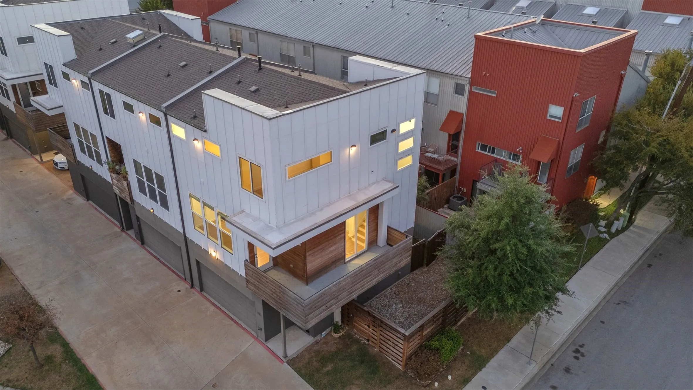 Aerial view of the end-unit condo showing the wraparound balcony, rooflines, fenced side yard and shade tree