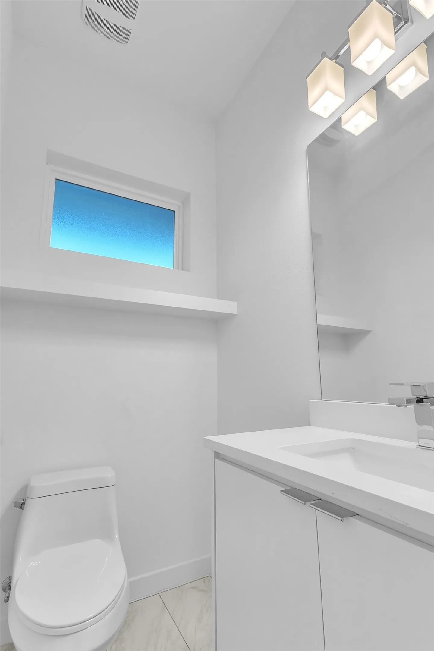 Powder room with a white vanity, one-piece toilet, frosted window and display ledge in this East Dallas condo
