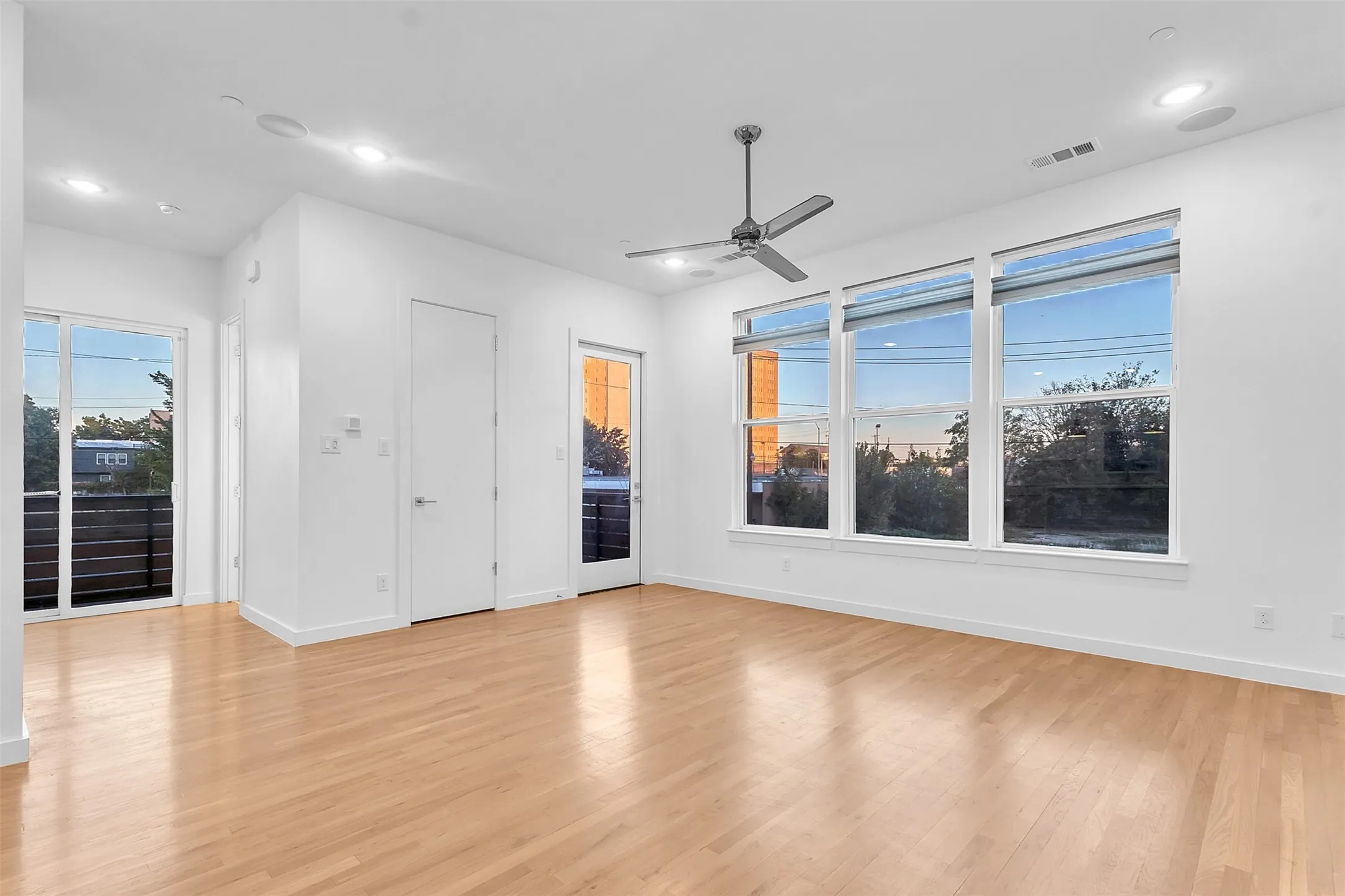 Living area with three large windows, two glass doors to the wraparound balcony and in-ceiling speakers