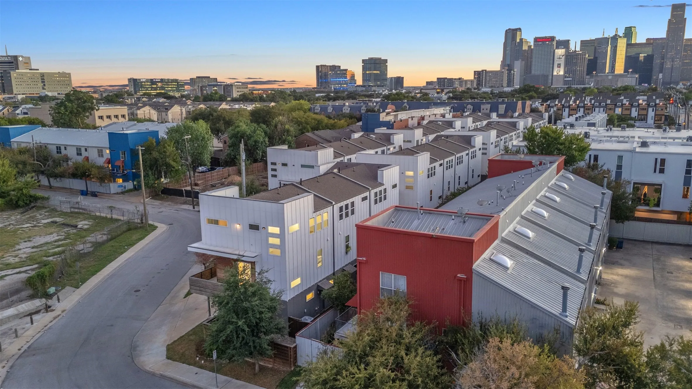Aerial view of the townhome-style condo community at dusk with the Downtown Dallas skyline on the horizon