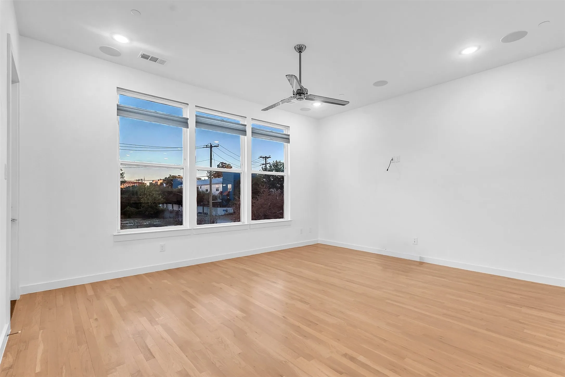 Living room in this East Dallas condo with a trio of windows, recessed lighting and a chrome ceiling fan