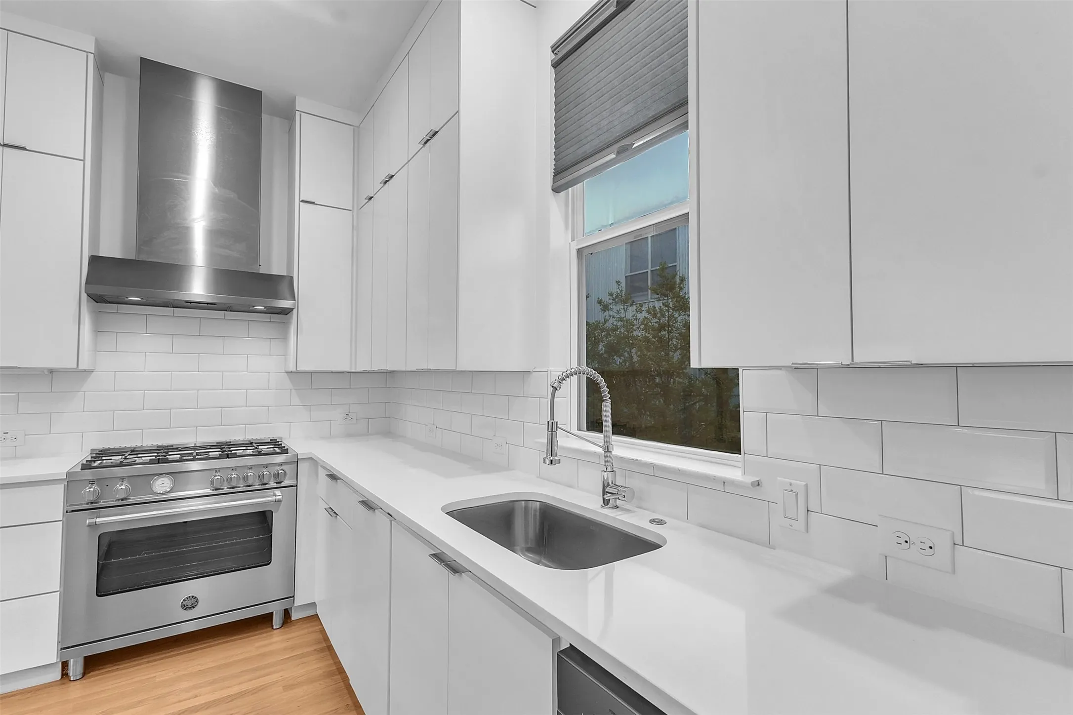 Kitchen sink wall with a stainless undermount sink, pull-down faucet, subway tile backsplash and shaded window