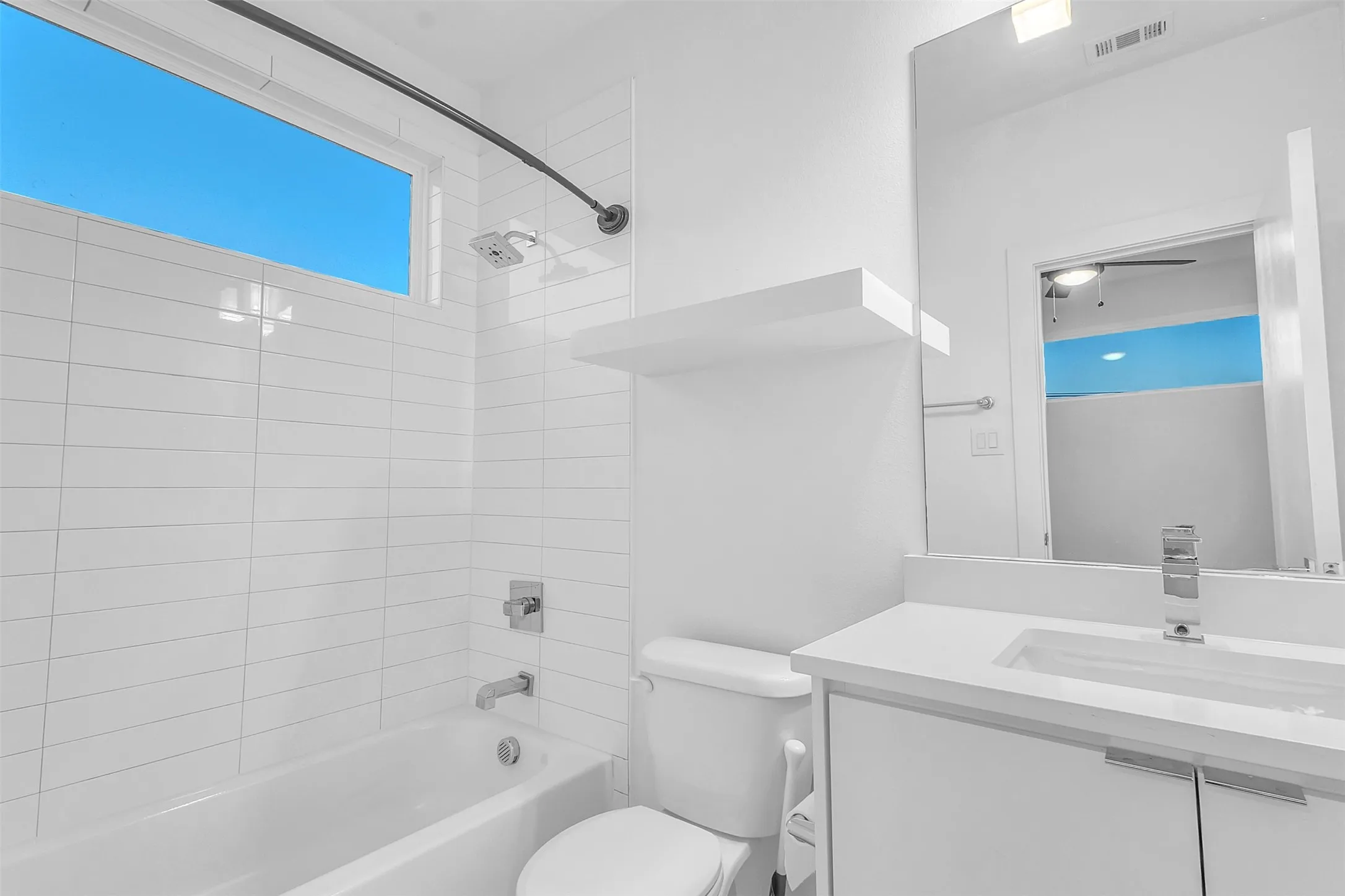 Secondary bath with a tub and shower combo, white subway-style tile, a floating shelf and single-sink vanity