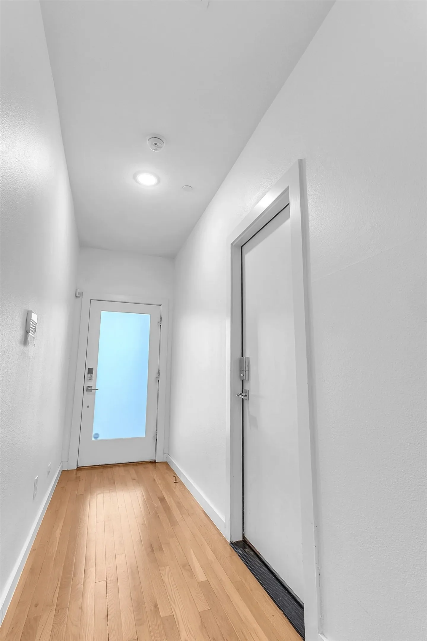 First-floor entry hall with wood-look floors, a glass front door with keypad lock and an interior keypad door