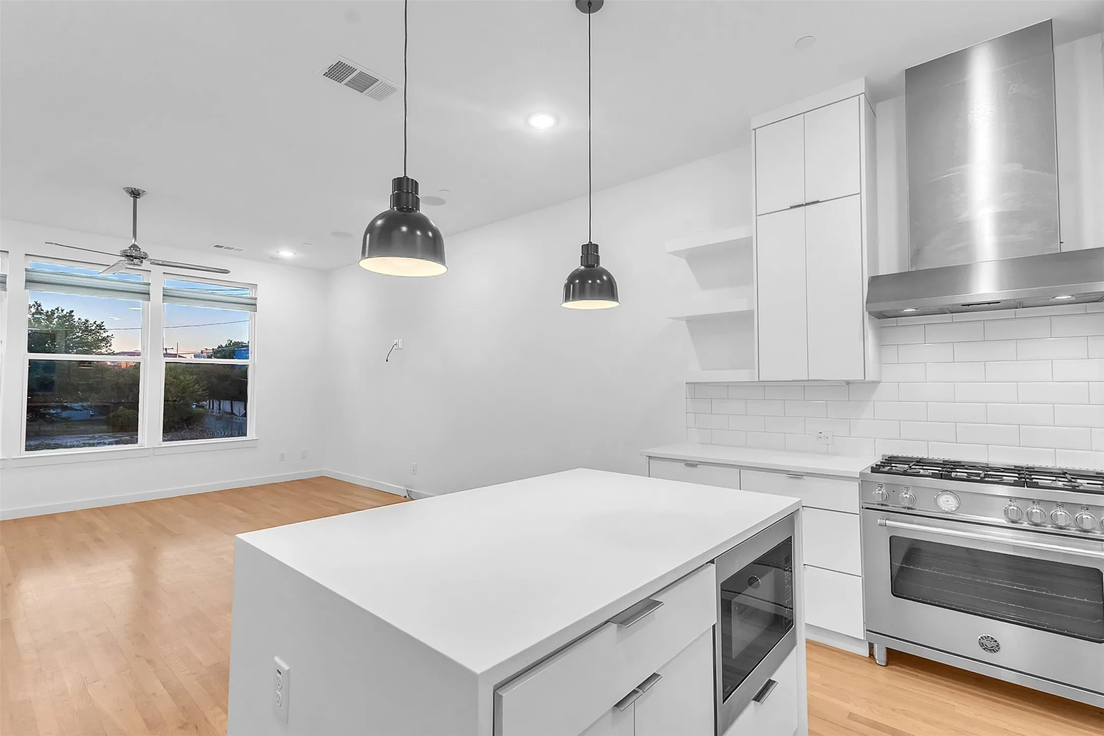 Kitchen island with a built-in microwave, plus a commercial-style gas range, stainless vent hood and open shelves