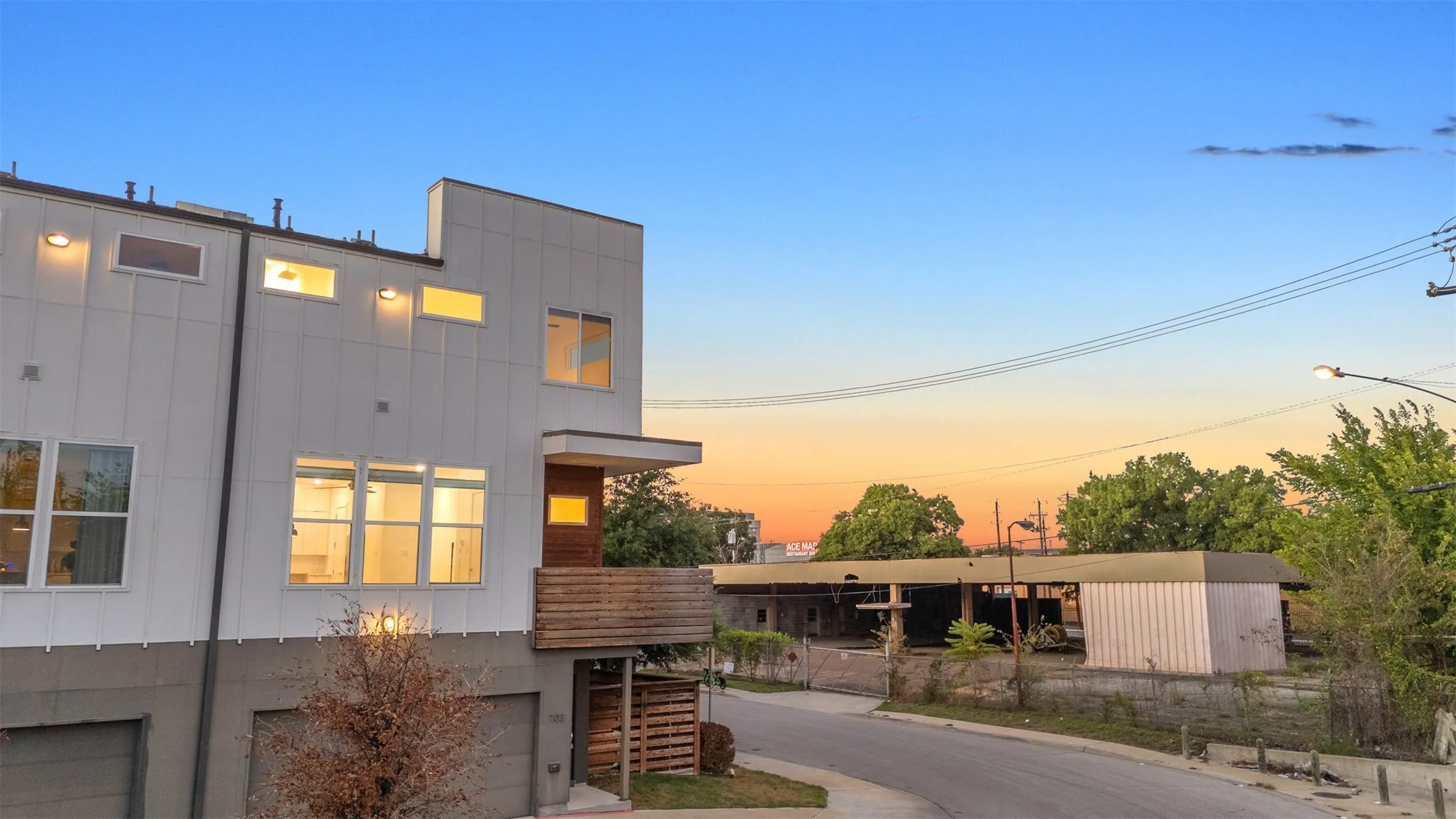 Corner end unit at sunset showing board and batten siding, the wood-clad balcony and the fenced side yard