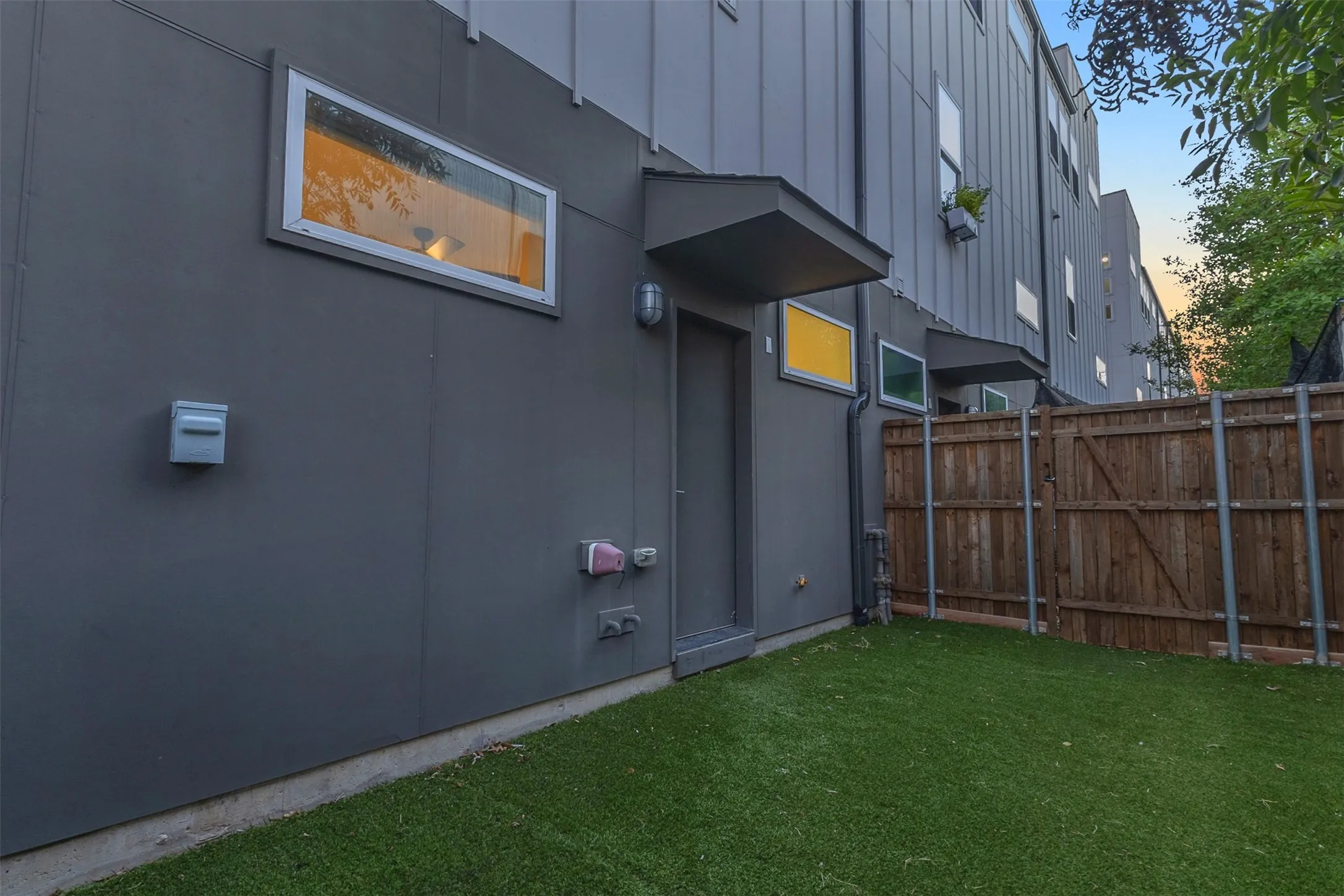 Private turf back yard with a covered rear entry door and a wood privacy fence at this Dallas condo