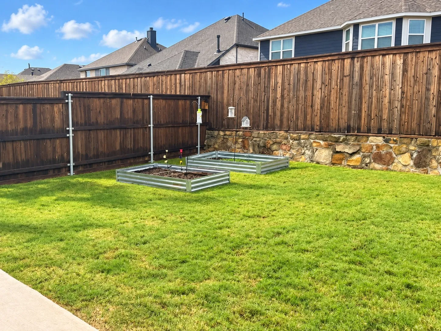 Expansive lawn area, wood privacy fencing, stone retaining wall, and two galvanized raised garden beds