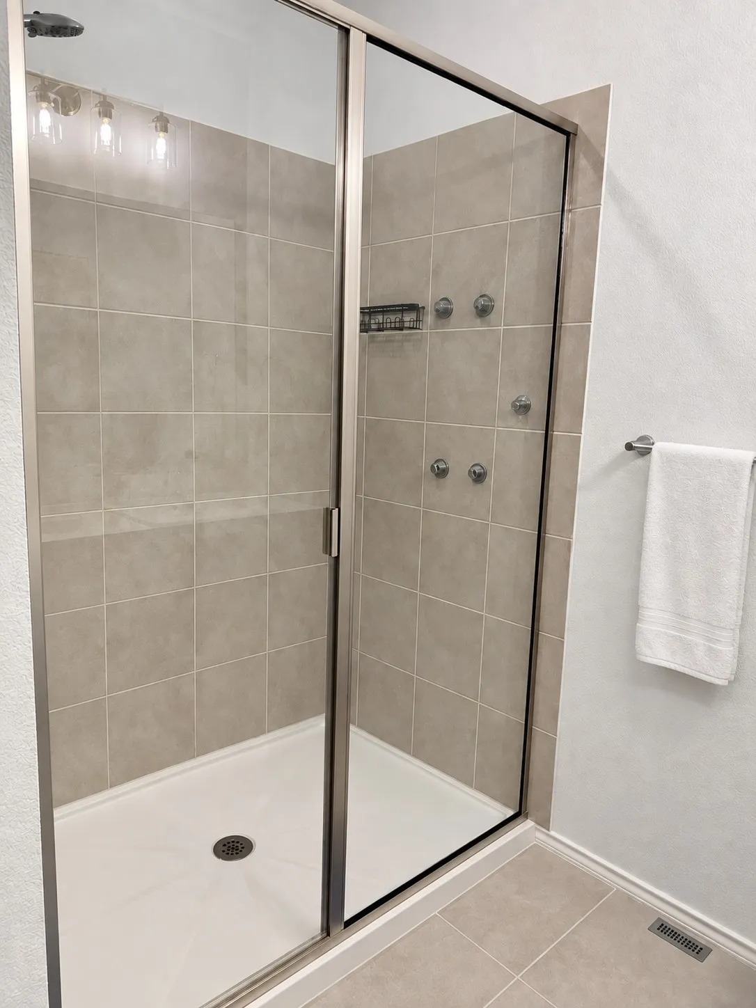 Glass-enclosed shower featuring a rain shower head, body jets, and tiled walls