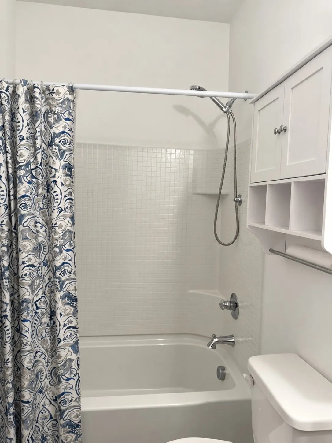 Bathtub with a tiled surround, chrome fixtures, and a multi-function showerhead
