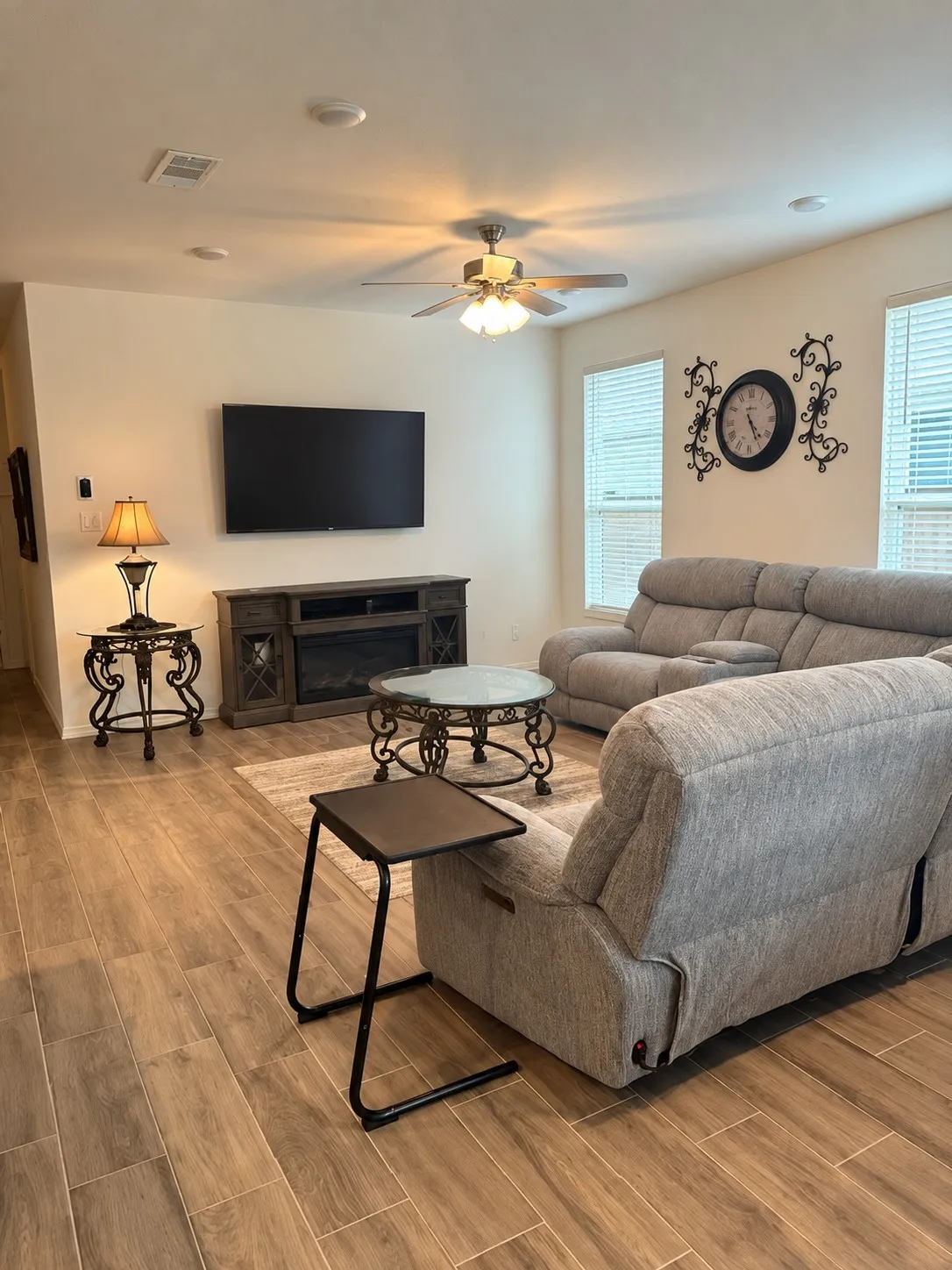Wood-finish flooring, recessed lighting, ceiling fan, multiple windows with blinds, and a built-in media console with an integrated fireplace