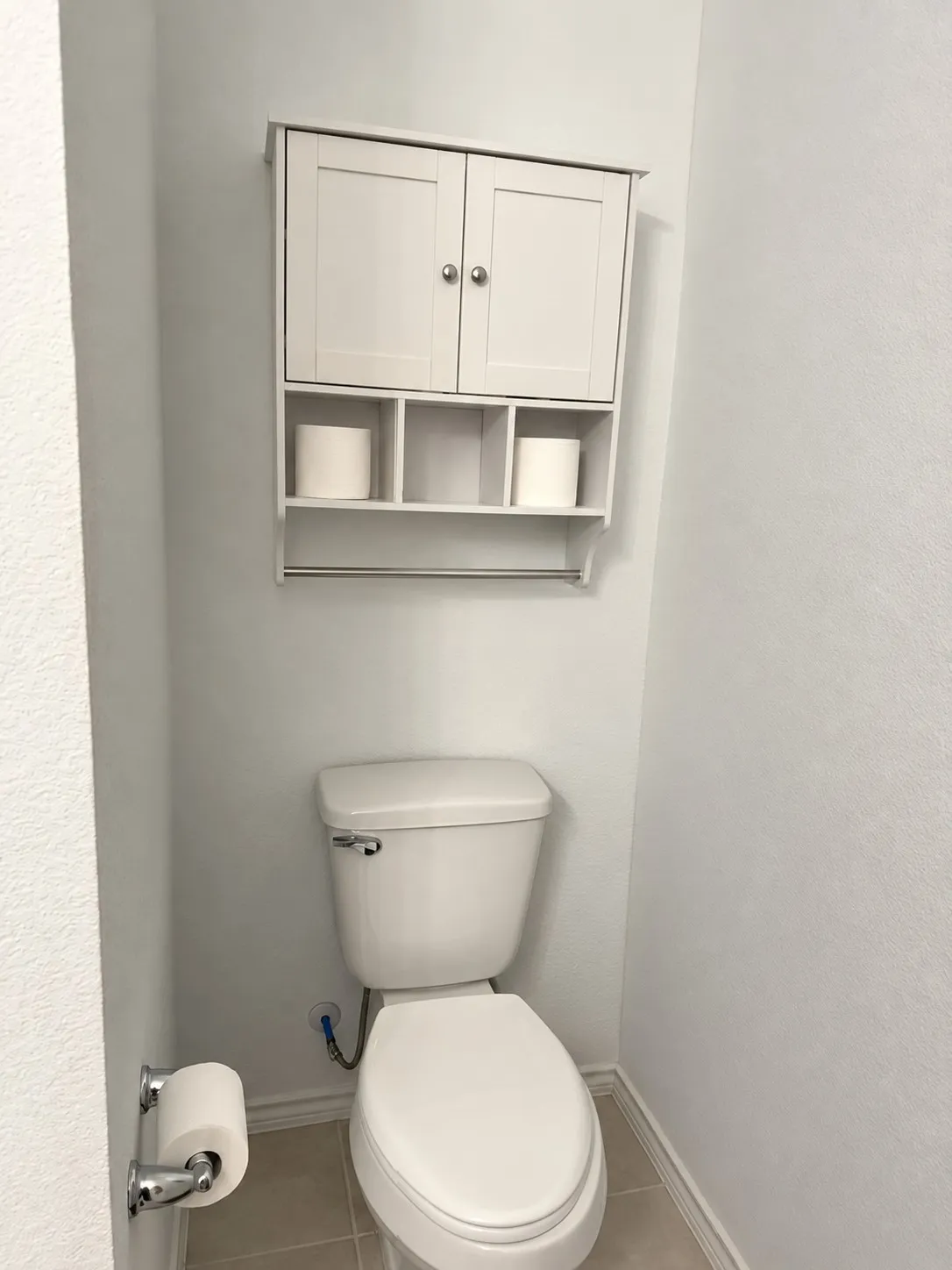 White wall-mounted cabinet with open shelving and towel bar