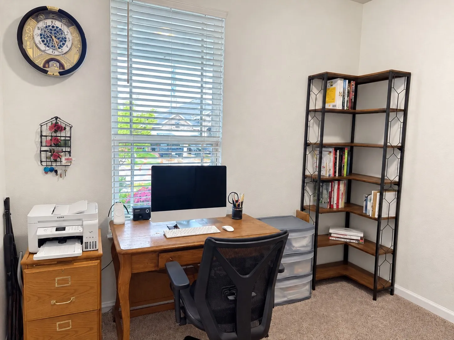 Neutral wall color, carpeted flooring, window with horizontal blinds, built-in corner shelving unit