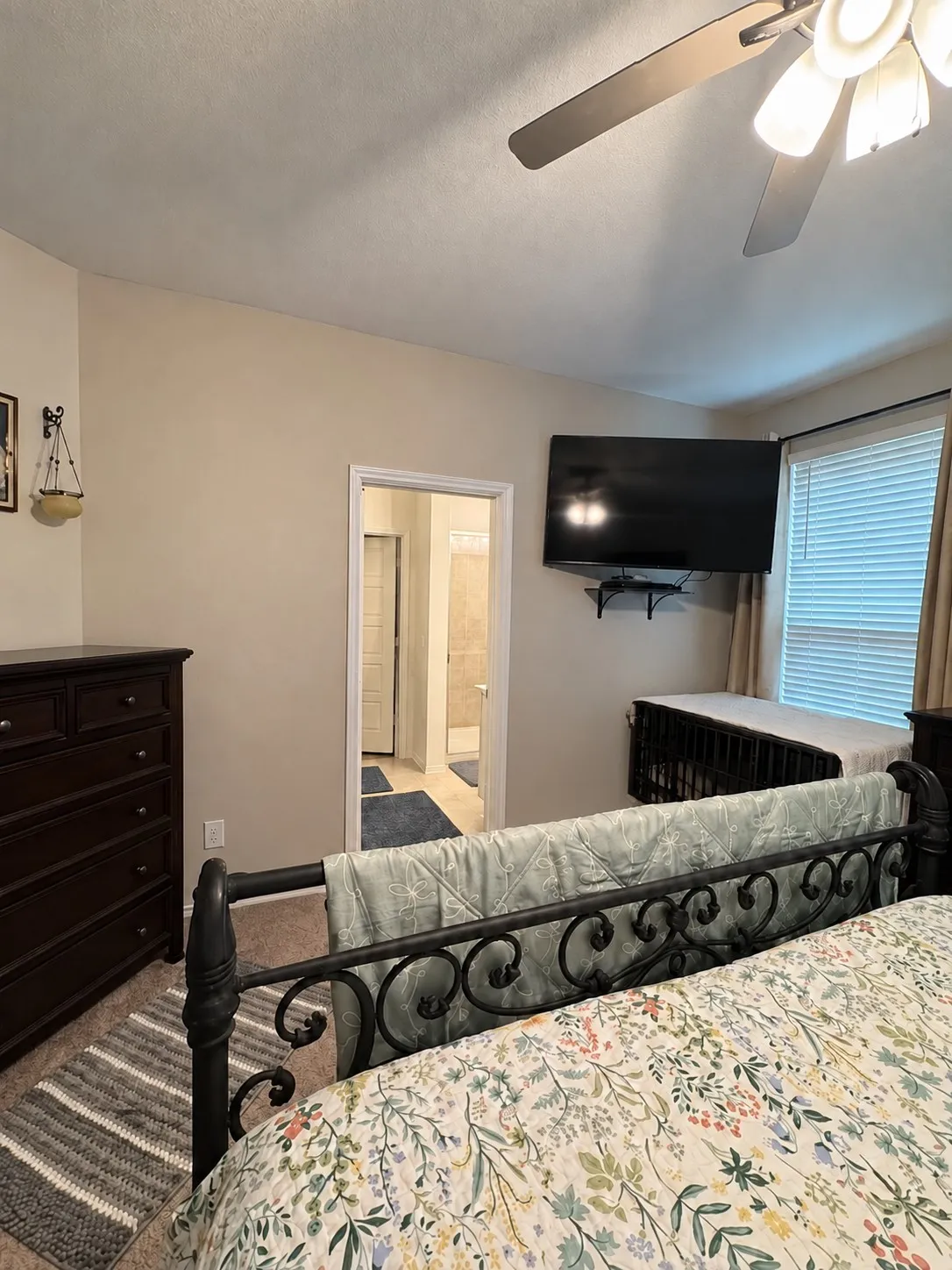 Carpeted room with a ceiling fan light fixture and a window with blinds and drapes