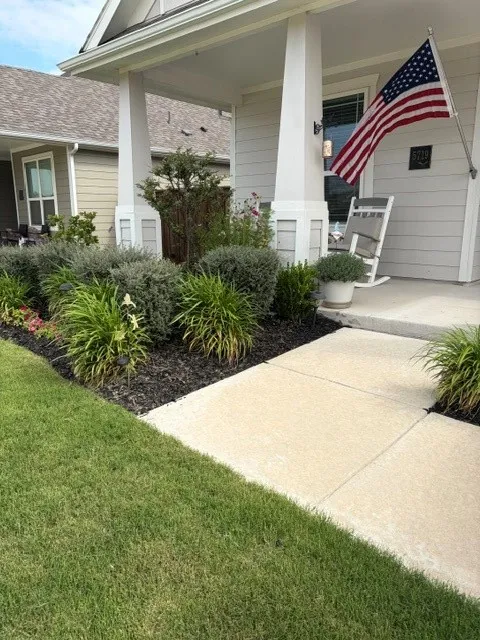 Covered front porch with decorative columns, well-maintained landscaping, and a concrete walkway