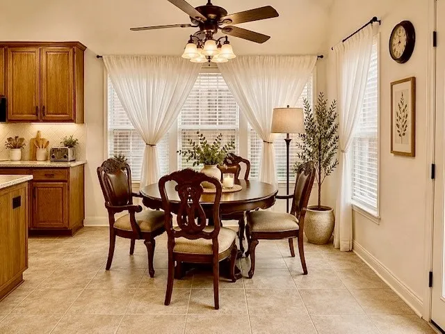 Recessed ceiling light fixture, tile flooring, wood cabinetry with under-cabinet lighting, and multiple windows with blinds