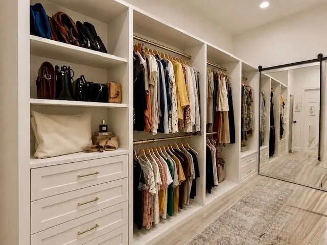 Custom built-in closet system featuring multiple shelving units, integrated drawers with gold-finish hardware, and dual hanging rods