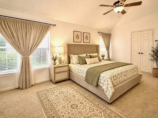 Vaulted ceiling featuring a ceiling fan, carpet flooring, windows with blinds and drapes, and paneled double doors