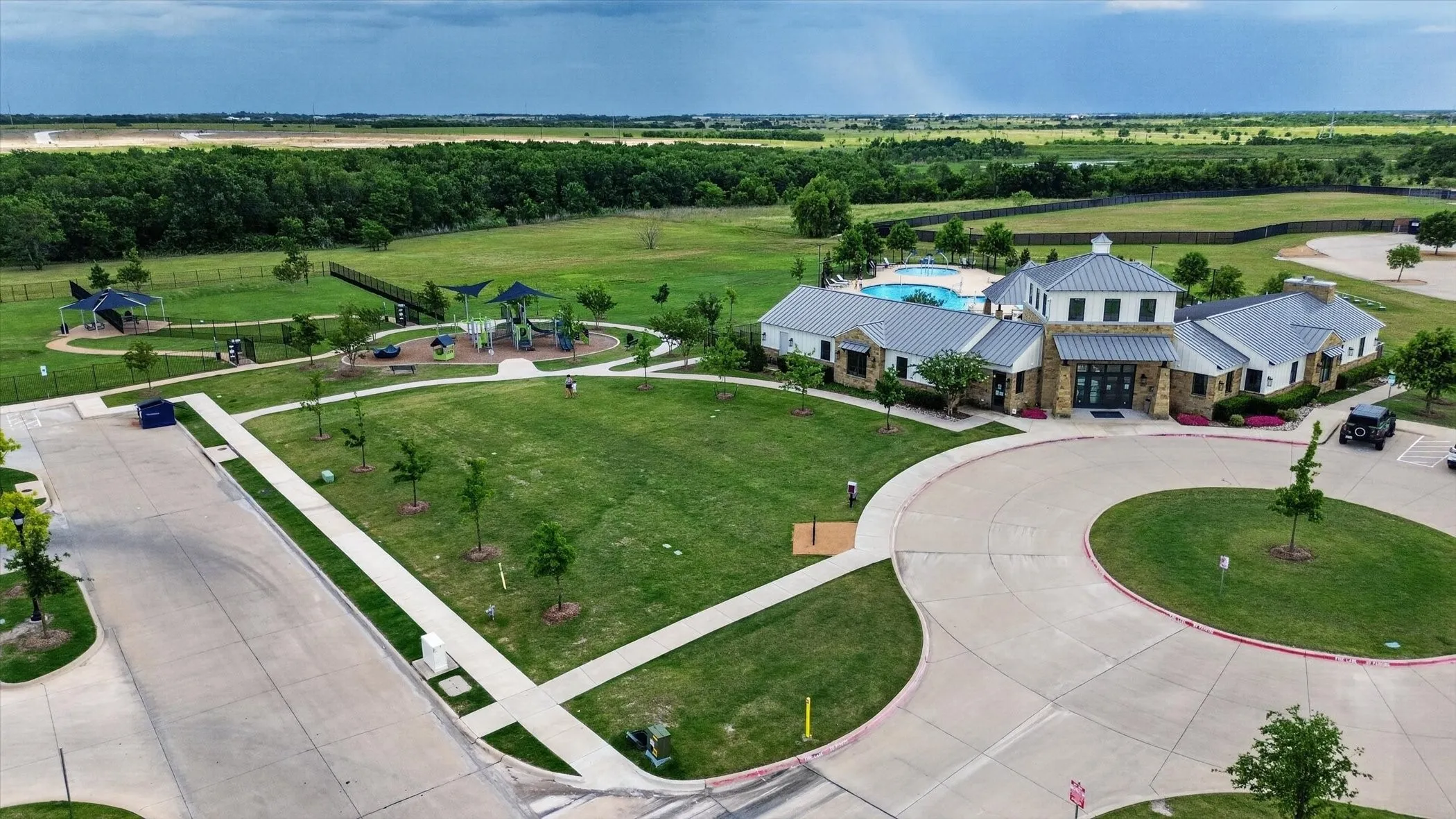Community amenity building with stone and siding exterior, metal roof accents, and a large swimming pool