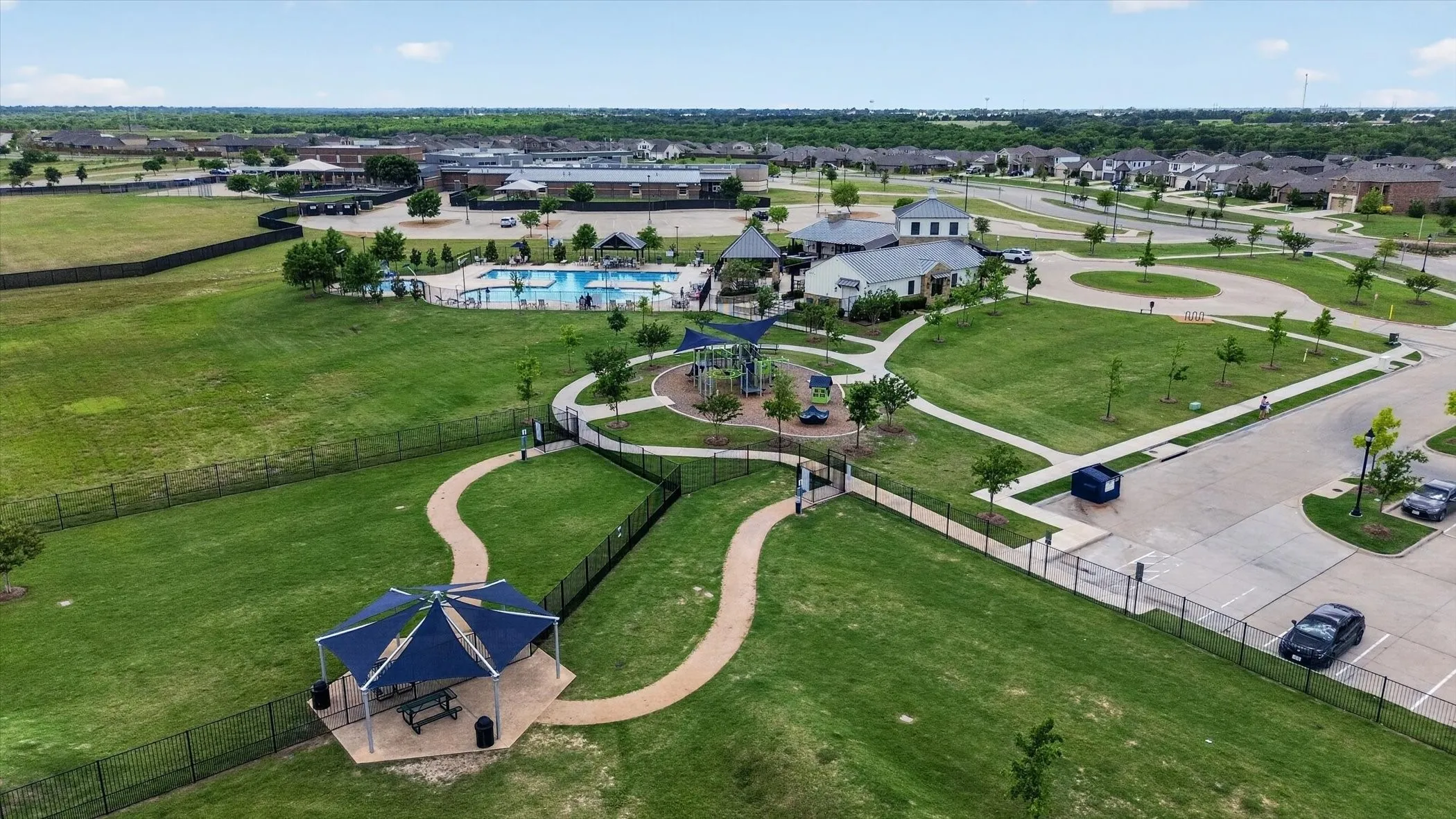 Expansive green spaces with walking paths, a dedicated playground area, a community swimming pool, and multiple residential structures