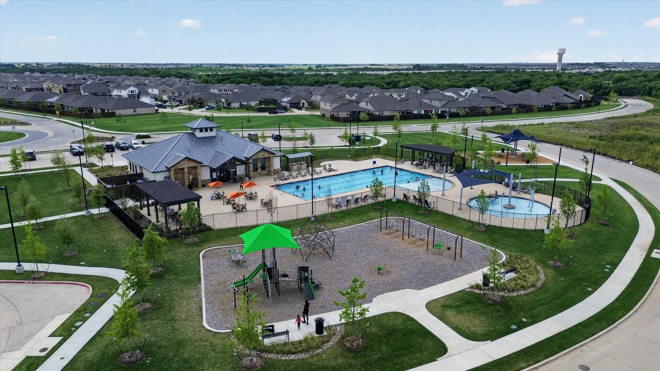 Community amenity center featuring a swimming pool, separate splash pad, and playground structure