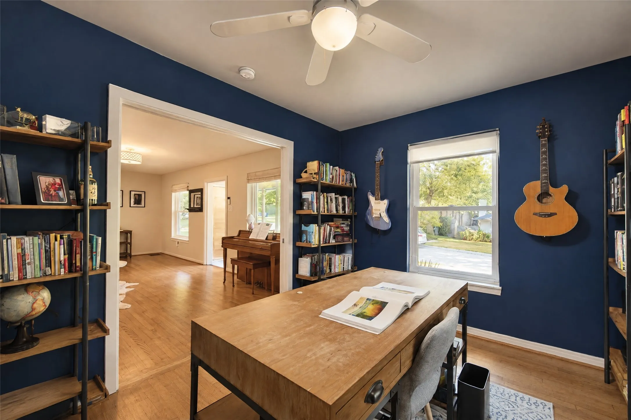 Bright room with a ceiling fan, dual windows, and built-in shelving, featuring wood-finish flooring