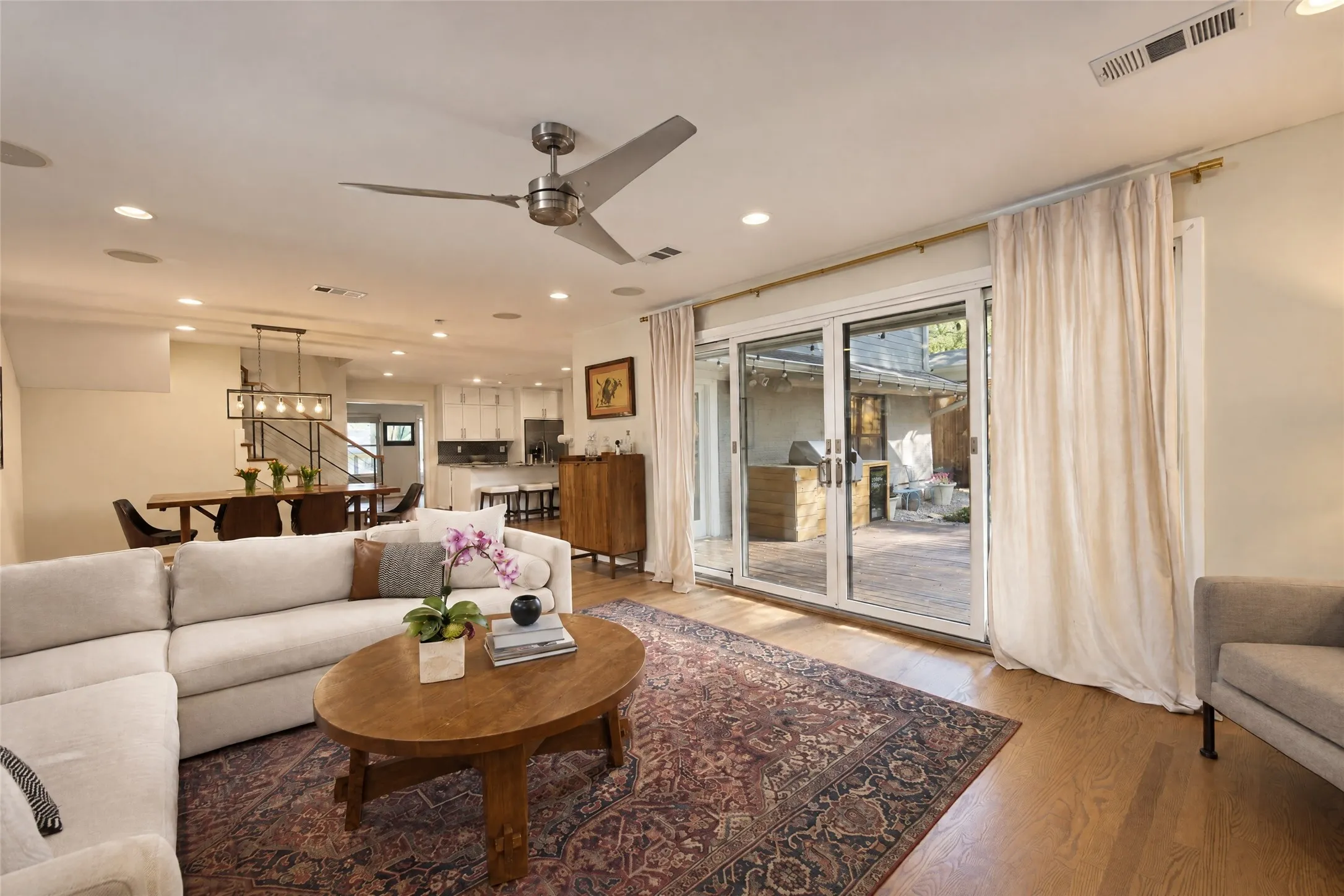 Open-concept living area featuring wood-finish flooring, a contemporary ceiling fan, recessed lighting, and sliding glass doors leading to an outdoor space