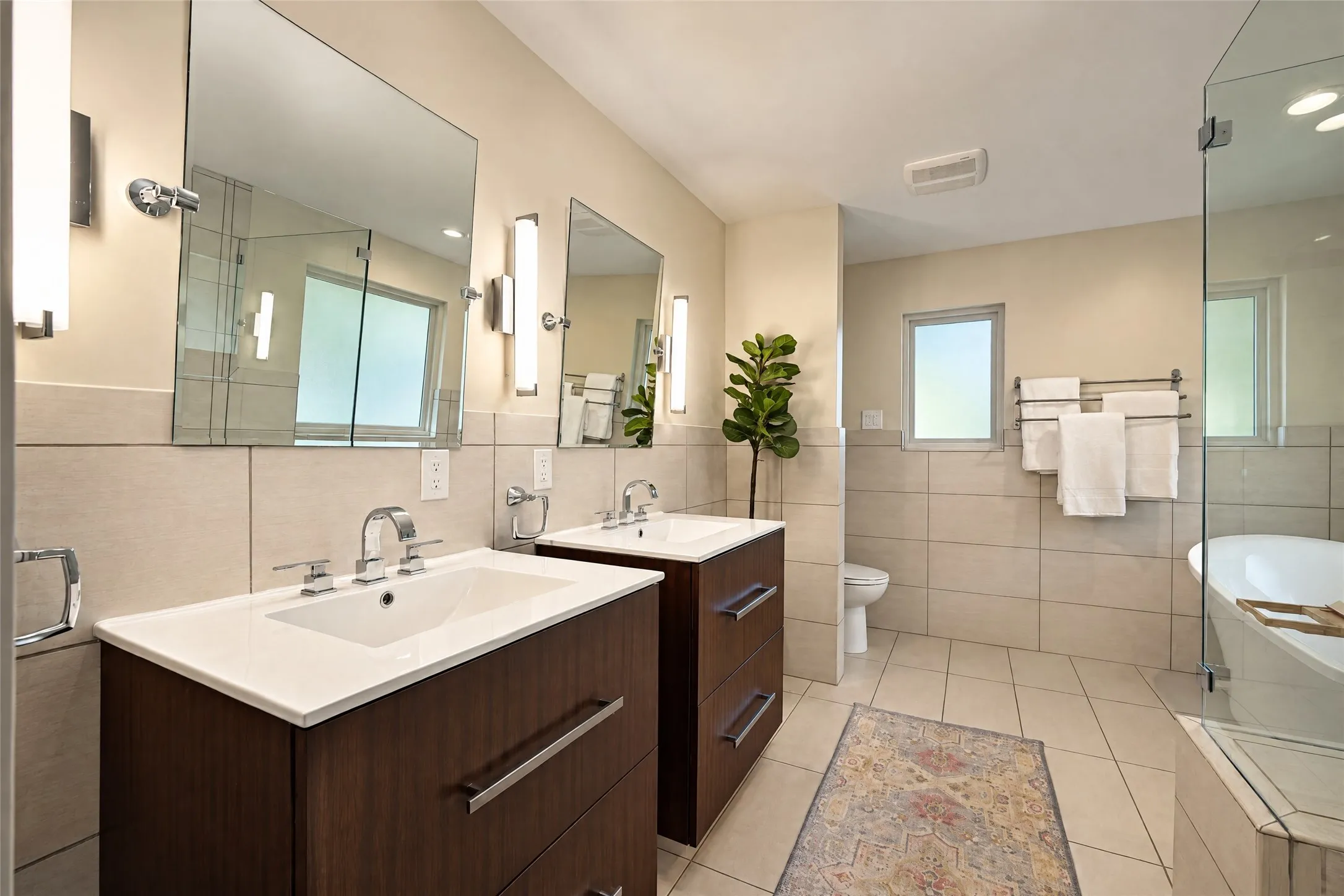 Dual vanity with wood-finish cabinetry, white countertops, and undermount sinks