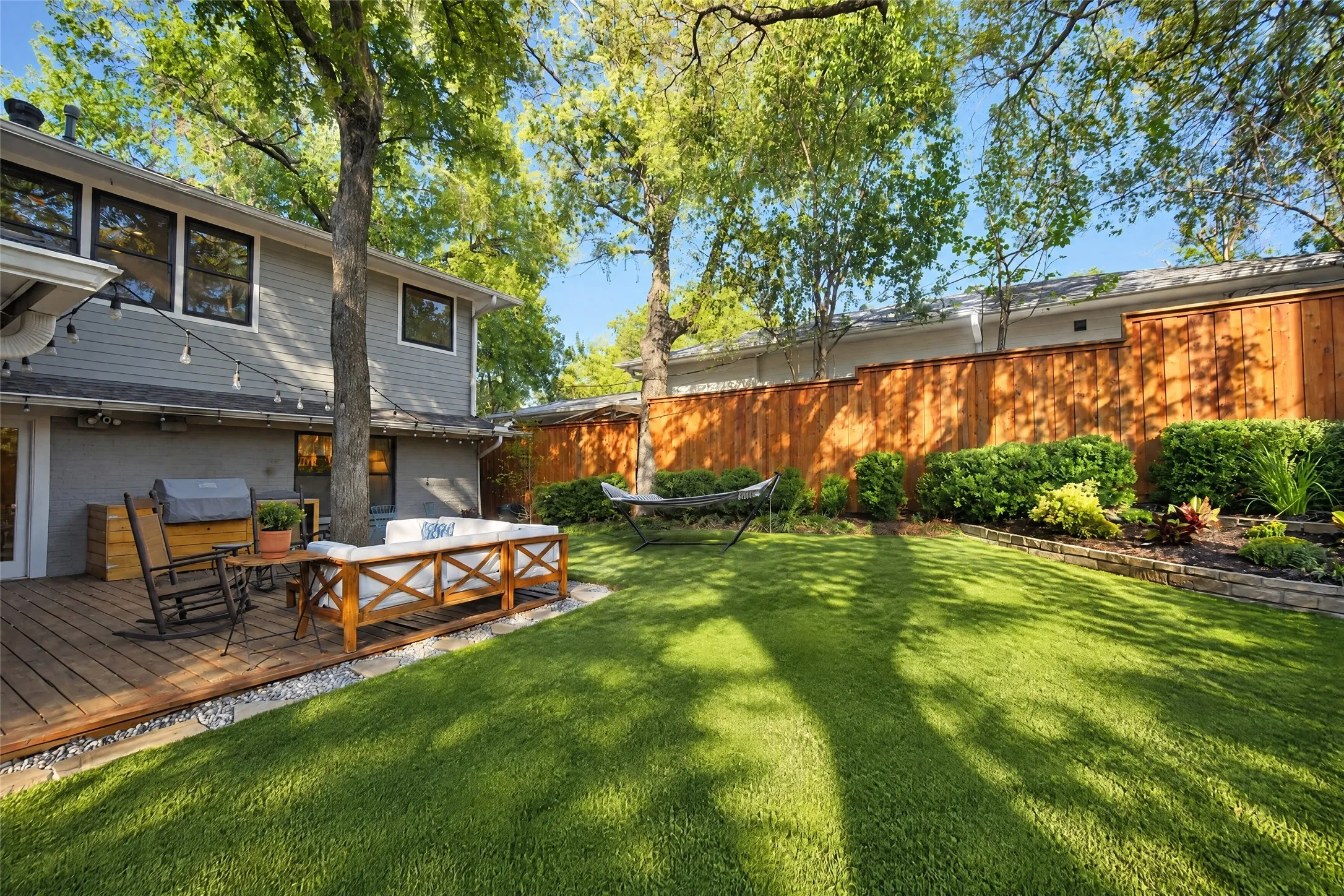 Expansive green lawn, wood privacy fencing, a wood-finish deck, and mature trees