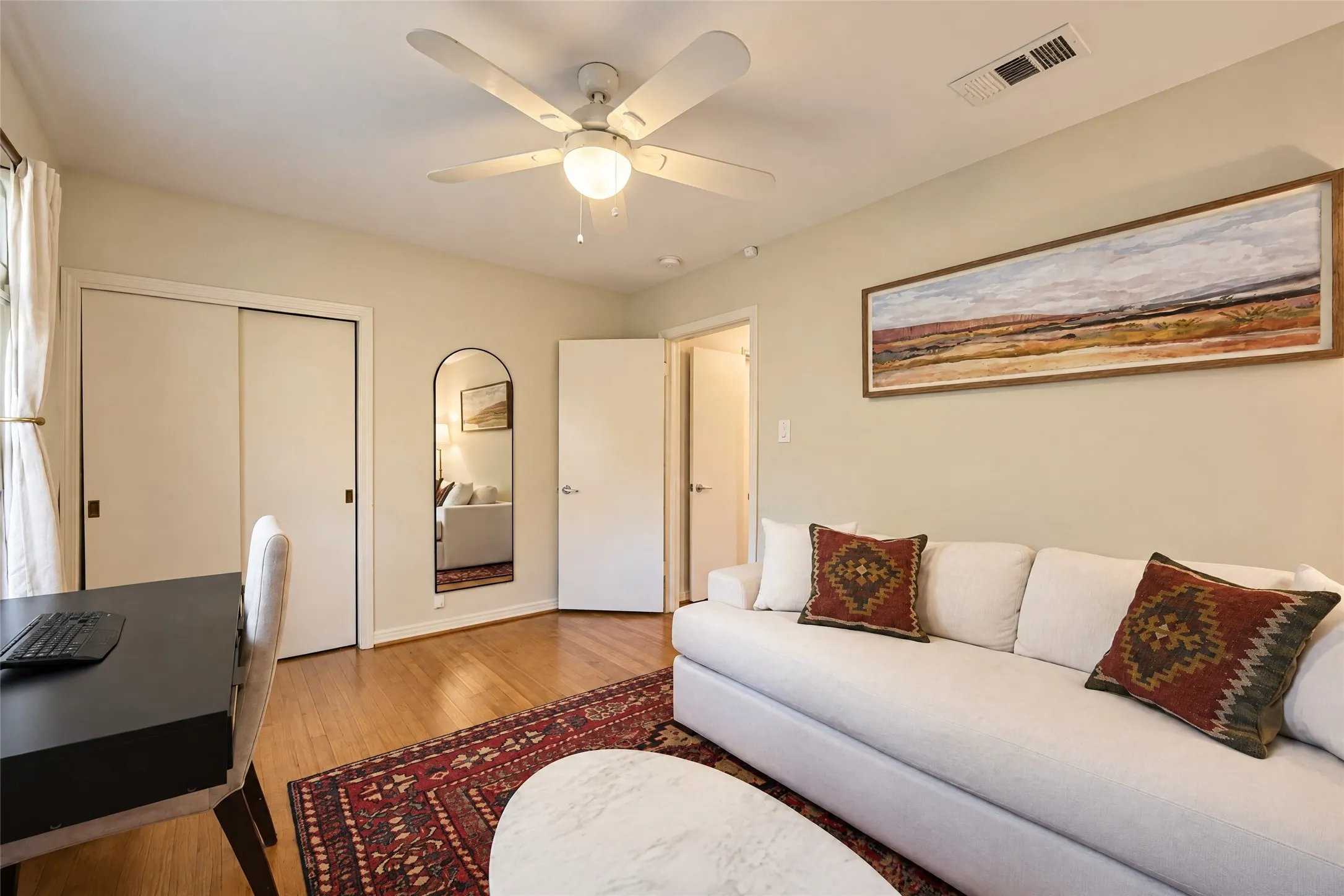 Wood-finish flooring, sliding closet doors, and an overhead ceiling fan with lighting