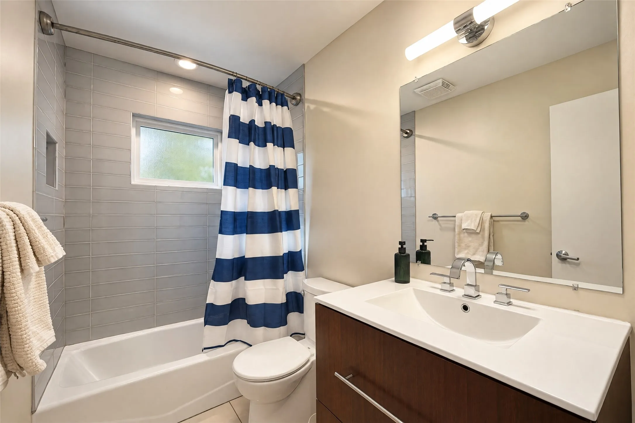 Bathroom featuring a wood-finish vanity with an integrated sink, polished chrome faucet, and a large wall mirror