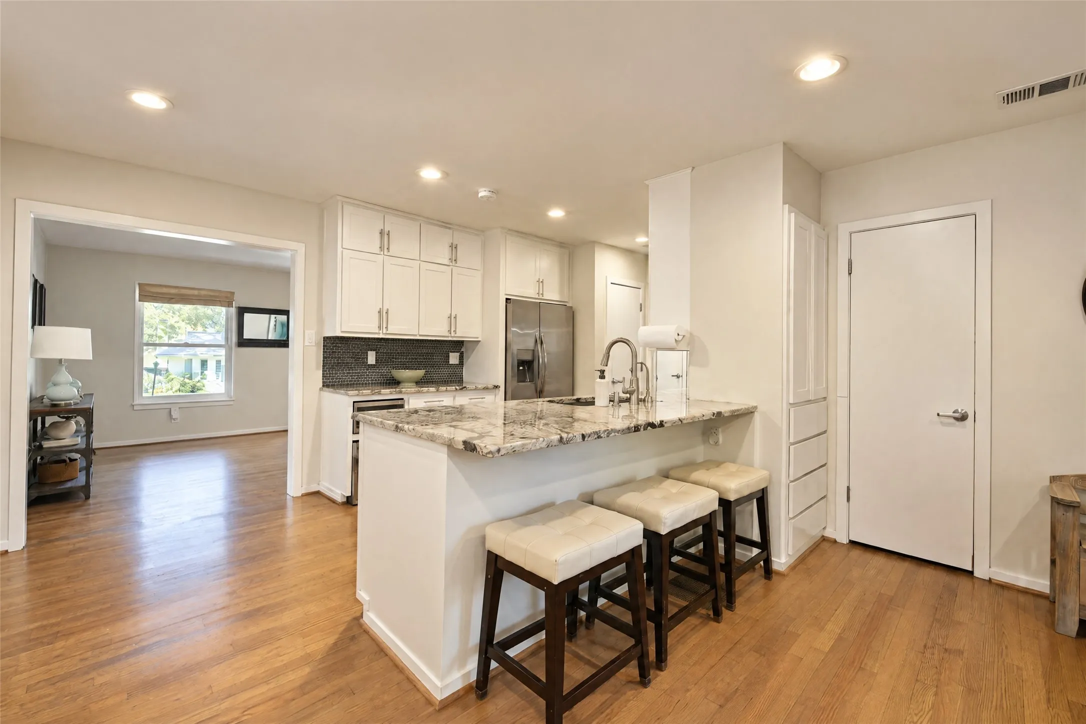 Kitchen featuring a granite-finish island with seating, stainless steel appliances, white cabinetry, and recessed lighting
