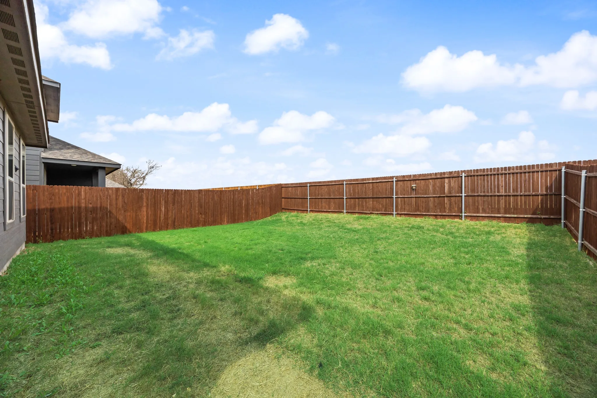 Expansive grassy yard with full privacy fencing