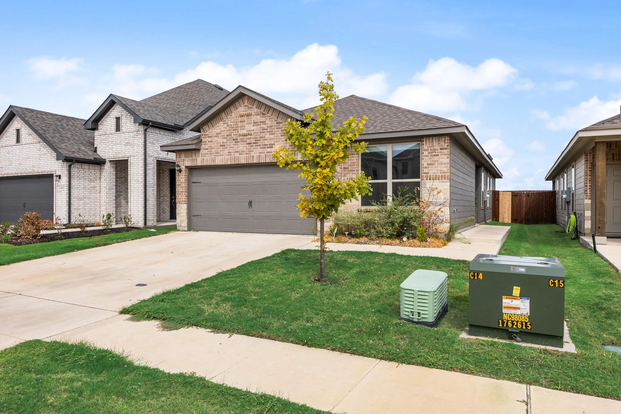Brick and siding exterior with a dark grey roof, a two-car garage, and a concrete driveway
