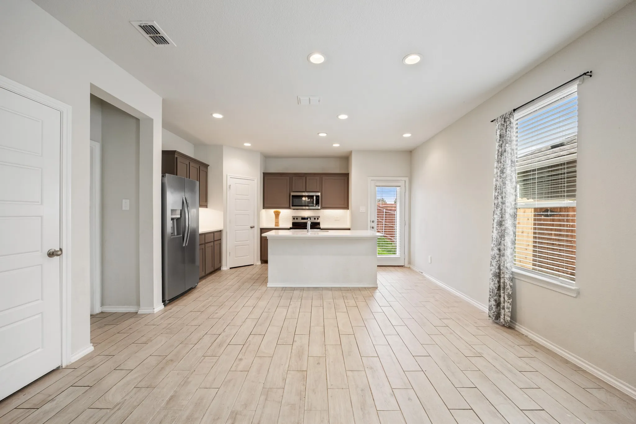 Spacious interior with wood-finish flooring, recessed lighting, and a kitchen island with seating