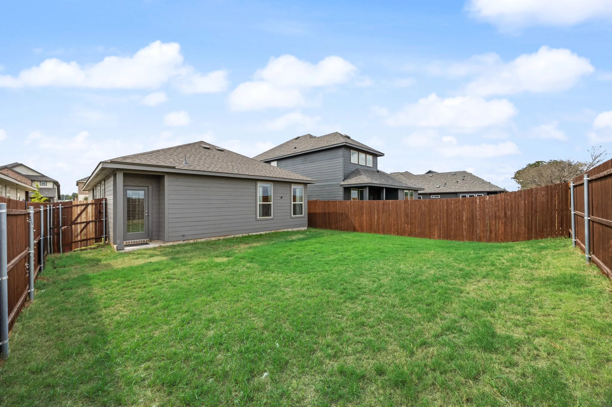 Expansive green lawn with a privacy fence