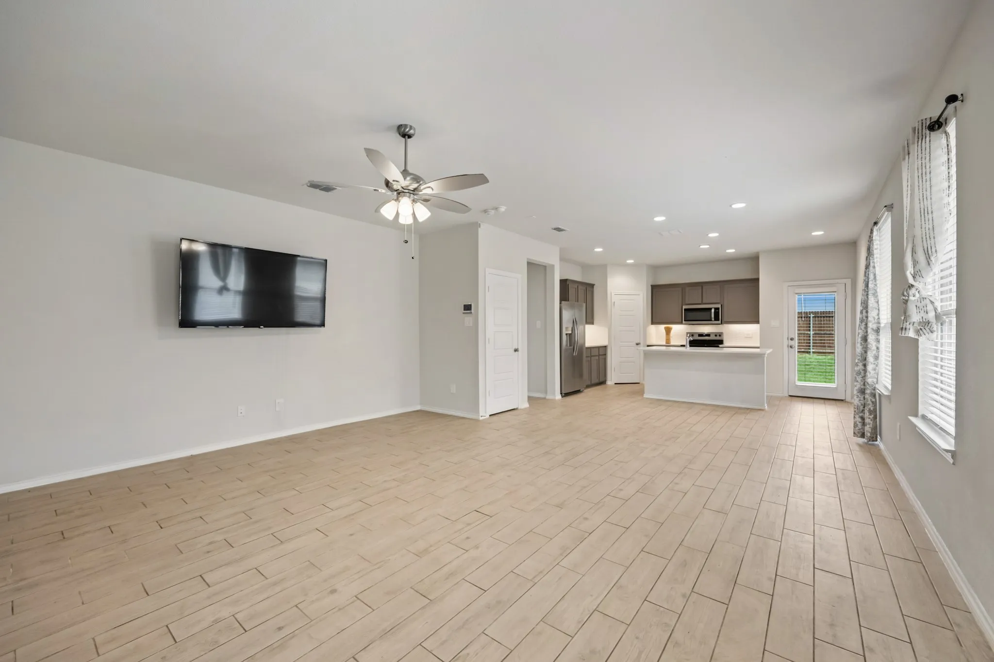 Open-concept living area featuring wood-finish flooring, recessed lighting, and a ceiling fan