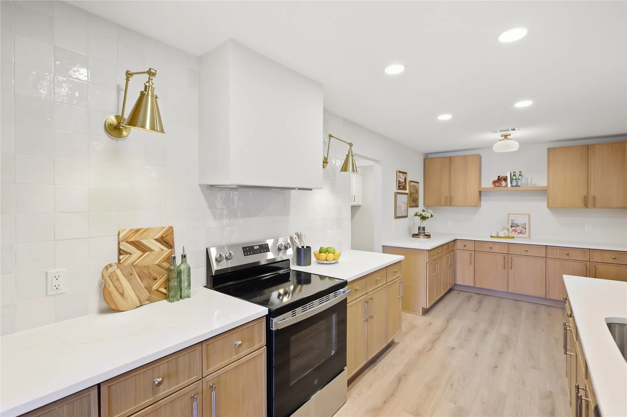 Contemporary kitchen featuring a stainless steel range, white countertops, wood-finish cabinetry, and recessed lighting