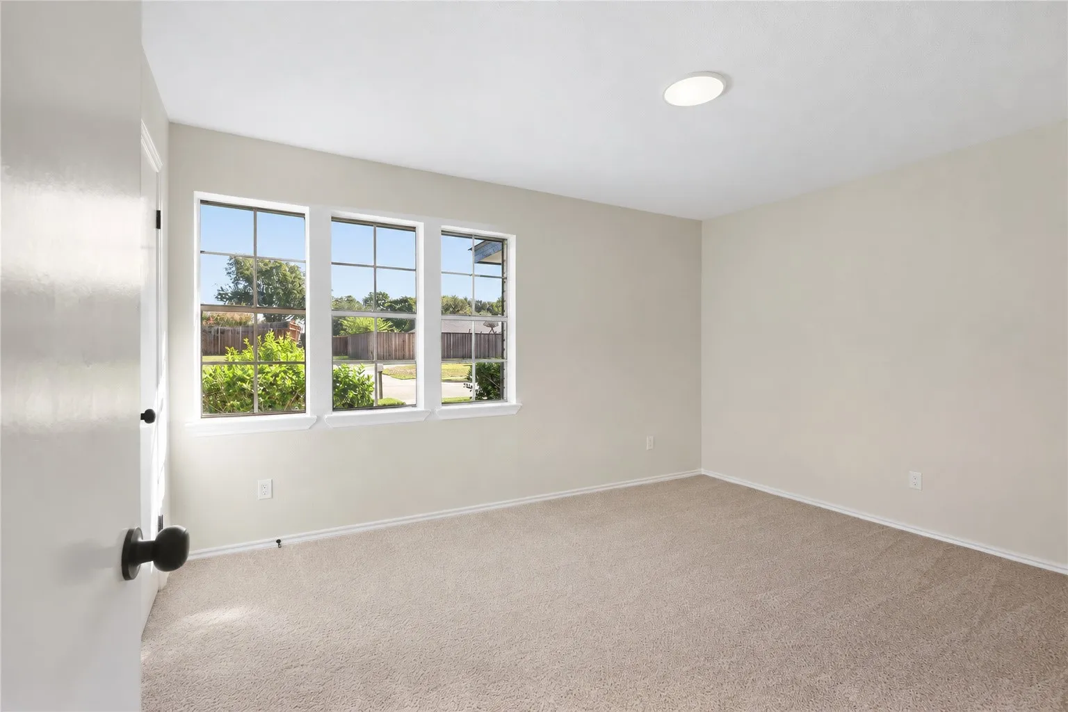 Neutral wall finishes, recessed ceiling lighting, light-toned carpet flooring, and a three-pane window with grid inserts