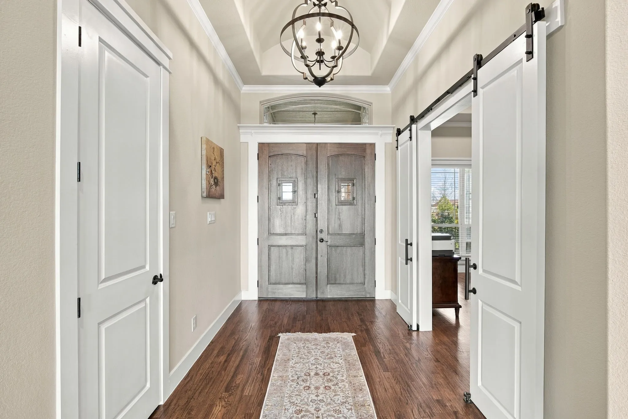 Love the double doors and wide entry way. Notice the ornate chandelier and sliding barn doors that lead to the office.