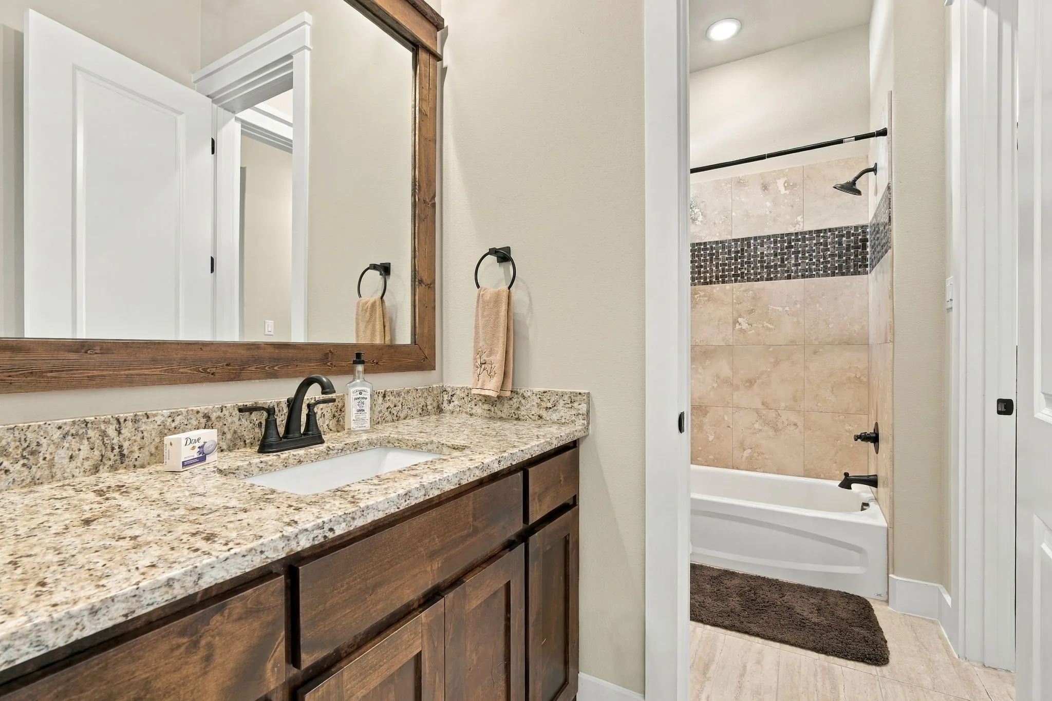 Jack and Jill bath connect tow both bedrooms. Spacious vanity with a granite countertop and decorative tile surround in bathtub.