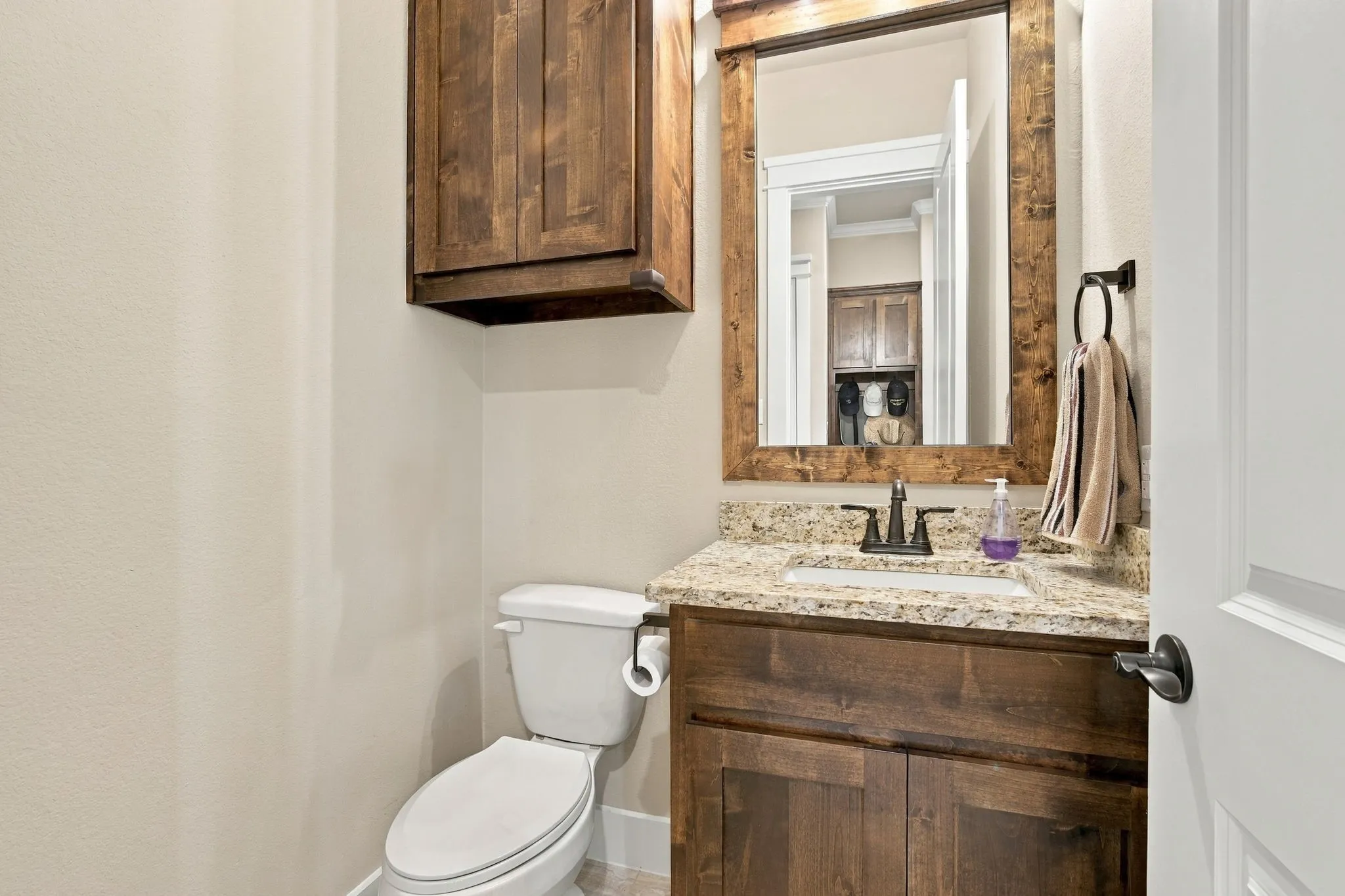 Having a half bath is ideal when guests are over. The extra cabinet is nice too! Granite countertops and a framed mirror elevate the space.