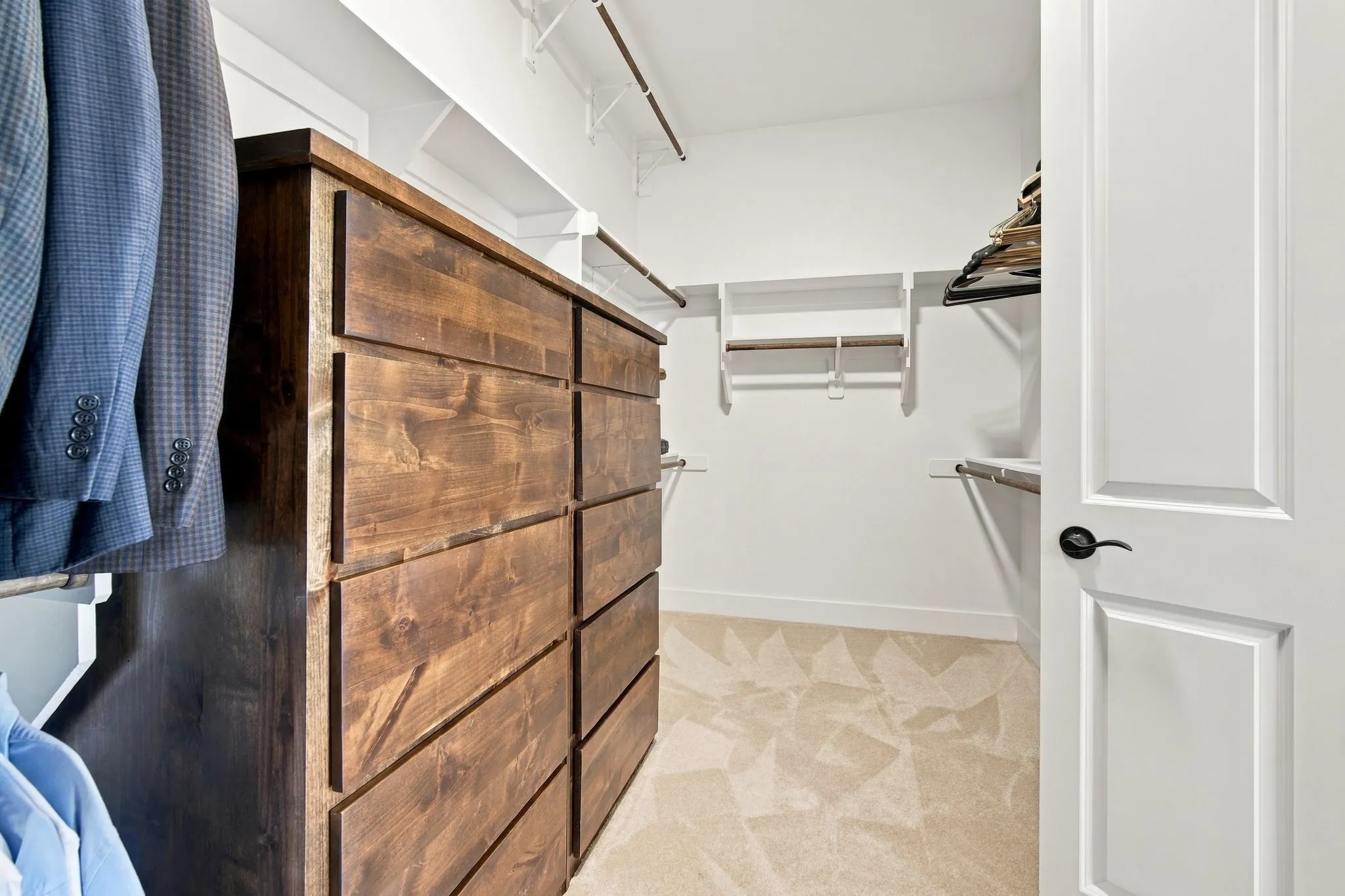 Spacious closet with two sides and a built-in wood-finish dresser with multiple drawers. Third hanging row for seasonal storage.